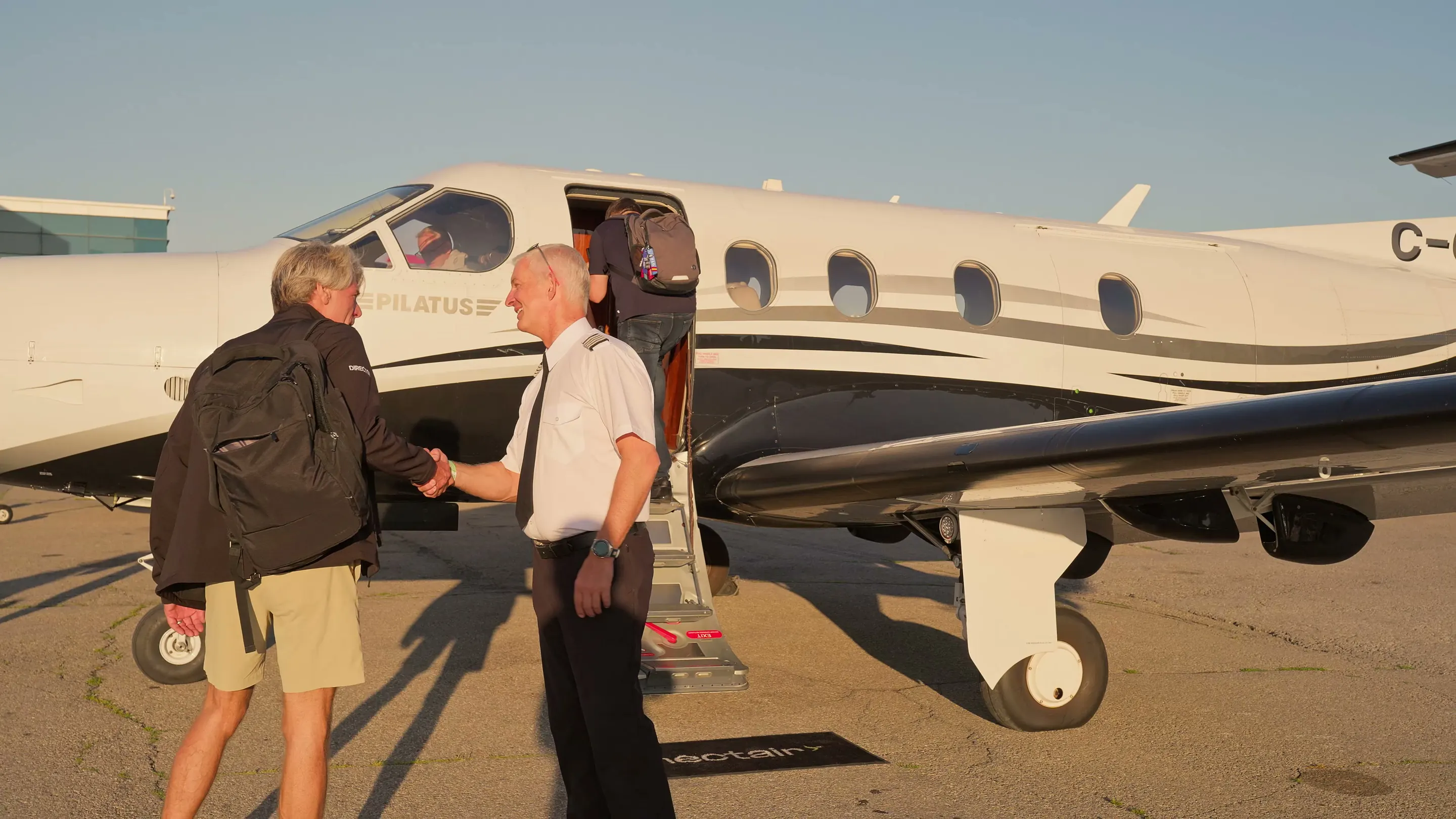 A NectAir captain shaking a passenger’s hand at the PC-12’s airstair