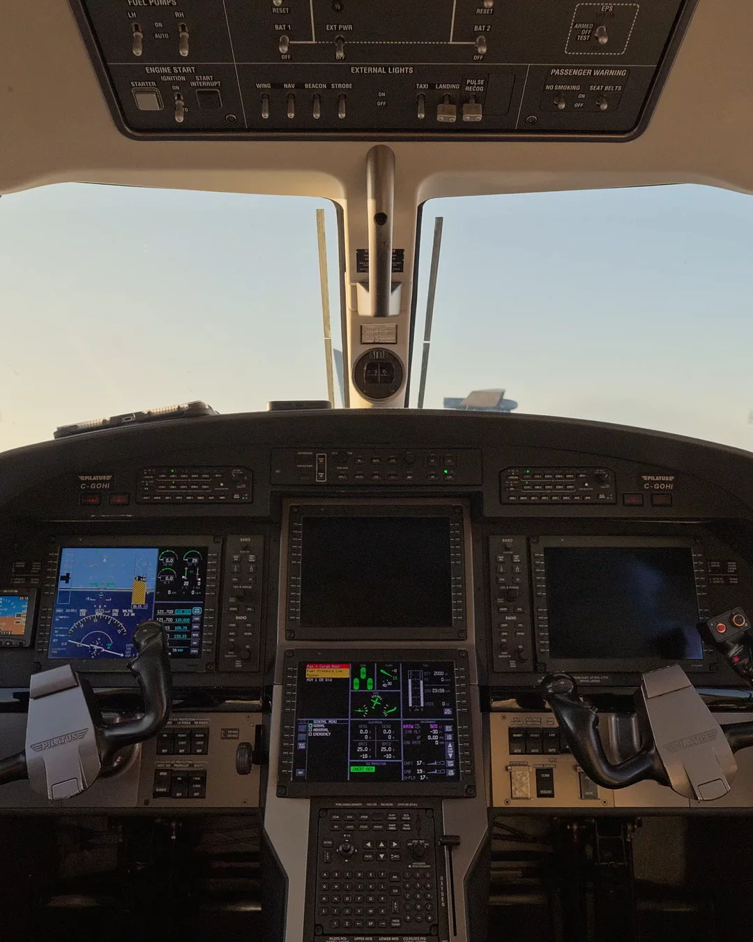 The flight deck of our Pilatus PC‑12: overhead panel, windshield and glowing avionics
